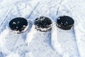 black hockey pucks lies on ice at stadium photo