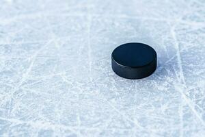 black hockey puck lies on ice at stadium photo