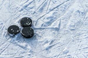 black hockey pucks lies on ice at stadium photo