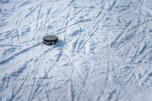 black hockey puck lies on ice at stadium photo