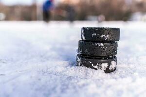 black hockey pucks lies on ice at stadium photo