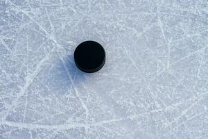 black hockey puck lies on ice at stadium photo