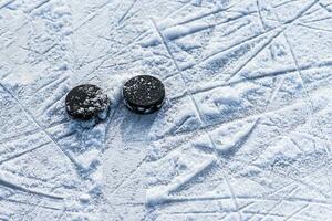 black hockey pucks lies on ice at stadium photo