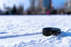 black hockey puck lies on ice at stadium photo