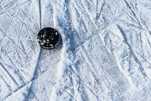 black hockey puck lies on ice at stadium photo