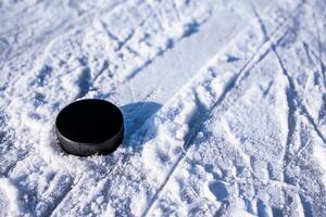 hockey puck lies on the snow close-up photo