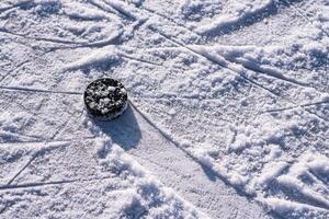 hockey puck lies on the snow close-up photo