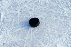 black hockey puck lies on ice at stadium photo