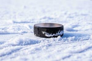 hockey puck lies on the snow close-up photo