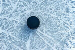 black hockey puck lies on ice at stadium photo