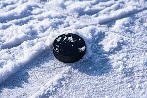 hockey puck lies on the snow close-up photo