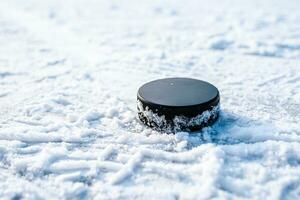 hockey puck lies on the snow close-up photo