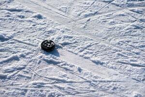 hockey puck lies on the snow close-up photo