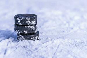 black hockey pucks lies on ice at stadium photo