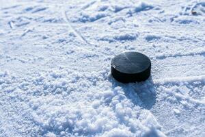 hockey puck lies on the snow close-up photo