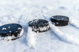 black hockey pucks lies on ice at stadium photo