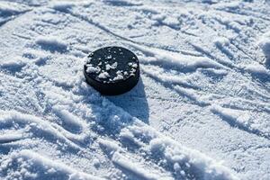 hockey puck lies on the snow close-up photo