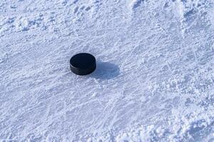 hockey puck lies on the snow close-up photo