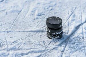 black hockey pucks lies on ice at stadium photo