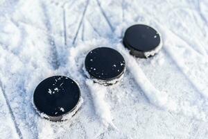 black hockey pucks lies on ice at stadium photo