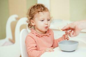 pequeño bebé come pasta en el para niños cocina foto