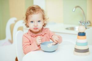 Little baby eats pasta in the children's kitchen photo