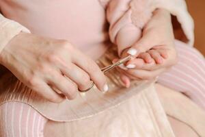 Caring mother cuts fingernails to little baby photo