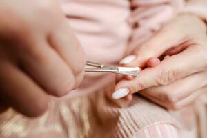 Mother cuts nails to little baby photo