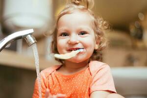 contento riendo bebé niña cepillado su dientes en el bañera foto