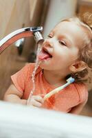 Cheerful happy child brushes his teeth in the morning in the bath photo