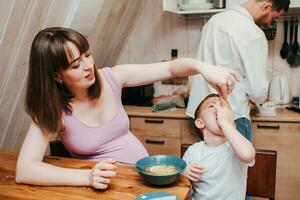 Happy child eats pasta in the kitchen with her family photo