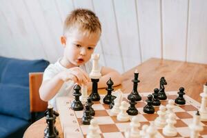 niño jugando ajedrez a hogar a el mesa foto