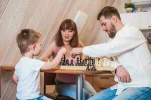 contento familia jugando ajedrez en el cocina foto