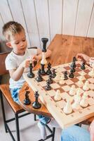 Little boy playing chess at home at the table photo