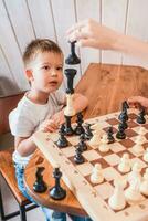 pequeño chico jugando ajedrez a hogar a el mesa foto