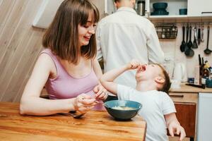 Mother with father feeding the child in the kitchen with pasta photo