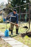 A man is planting a young tree. The farmer is digging the ground with a shovel for a small seedling. The concept of protection of the environment and ecology photo