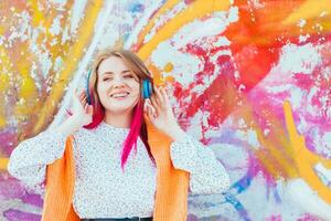 Portrait of a young laughing girl with braces listening to music in headphones in the summer on the street photo