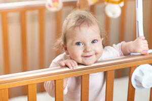 Portrait of a laughing baby who is standing in a crib photo
