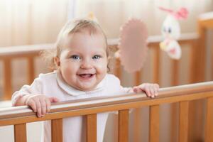 Portrait of a happy and laughing toddler girl in a crib photo