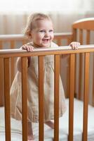 Happy and laughing little girl playing in her crib in the bedroom photo