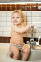 linda bebé jugando en el cocina lavabo foto
