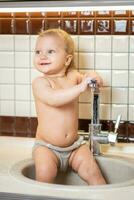 Cute baby playing in the kitchen sink photo