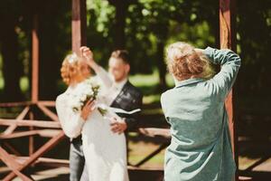 A wedding photographer photographs a couple in nature on a sunny day photo