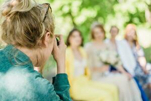 The wedding photographer photographs the guests of the bride and groom in nature photo