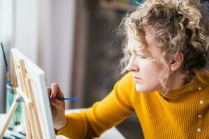 retrato de un artista niña quien crea un pintura a hogar foto