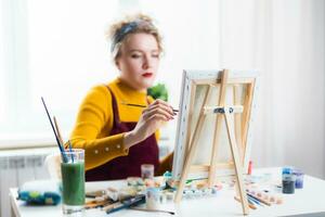 Beautiful woman artist paints on canvas at home photo