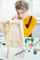 mujer sentado en frente de un pintura y pintura con cepillos en lona a hogar foto