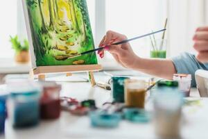 mujer sentado en frente de un pintura y pintura con cepillos en lona a hogar foto