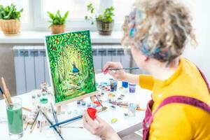 Curly blonde woman painting a picture by the window photo